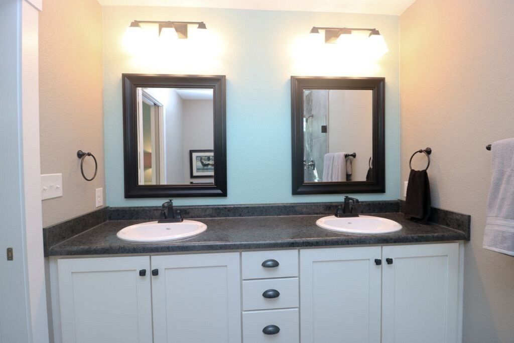 Une salle de bain avec deux lavabos, un miroir et un porte-serviettes.