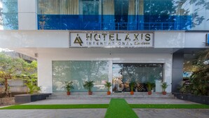 The entrance of Hotel Axis International with a modern facade, large glass windows, and a green lawn in front. - Hotel Axis International (Mumbai)