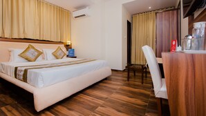 A hotel room with a large bed, a wooden desk, a chair, and a television. - Hotel Axis International (Mumbai)