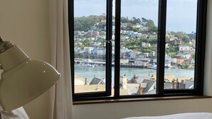 Ett hotellrum med ett stort fönster som erbjuder utsikt över en kuststad och hamn.
