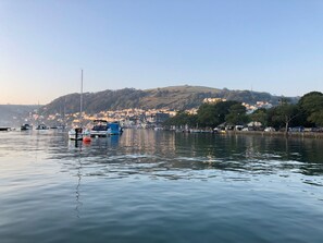 Overlooking a serene harbor, this property offers stunning views of boats moored in calm waters and a picturesque town on the hillside.