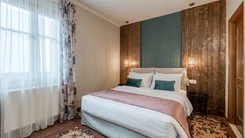 Un dormitorio con cama, cortinas, mesita de noche y lámpara de pared.