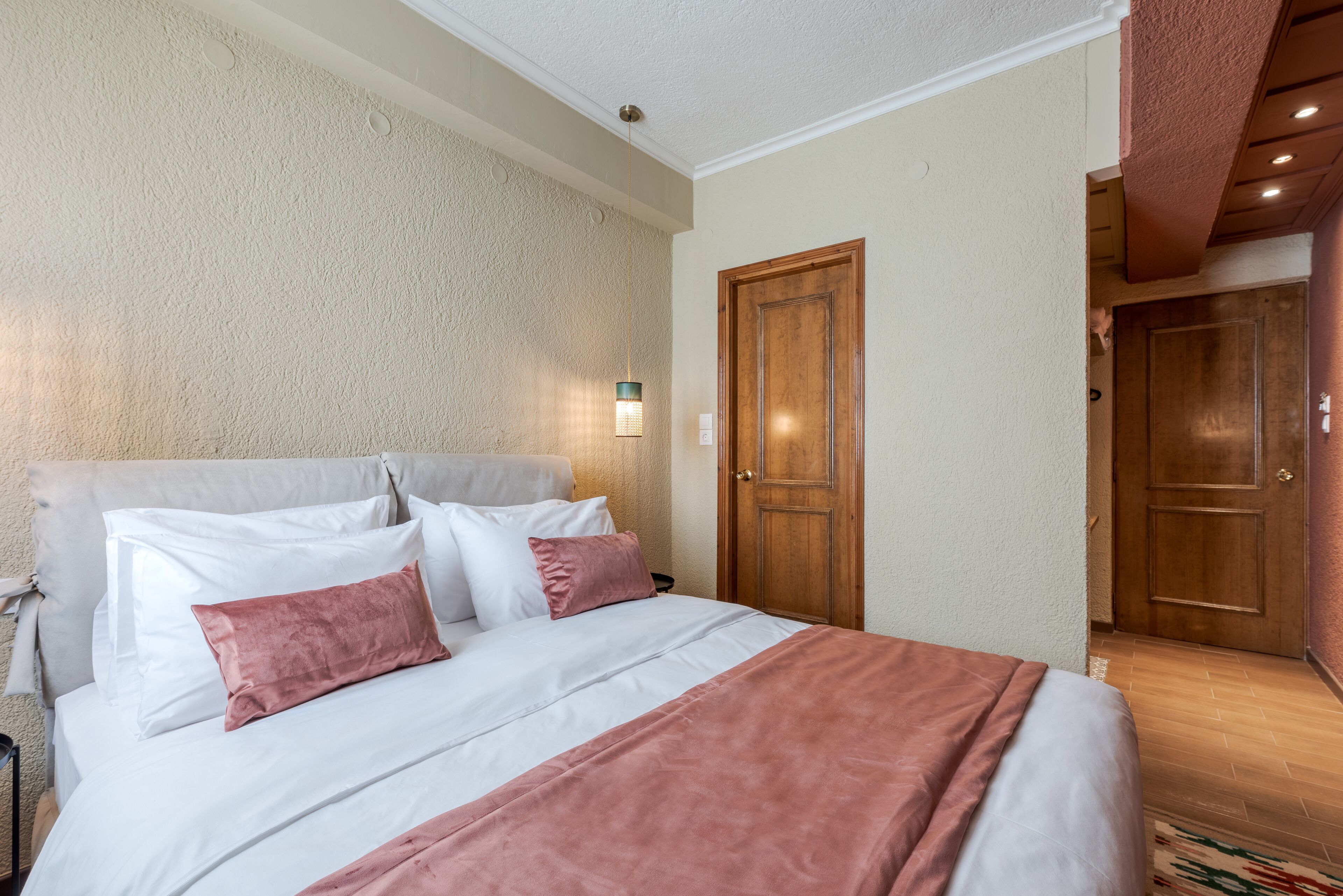 A hotel room with a large bed, a wooden door, and a textured wall.