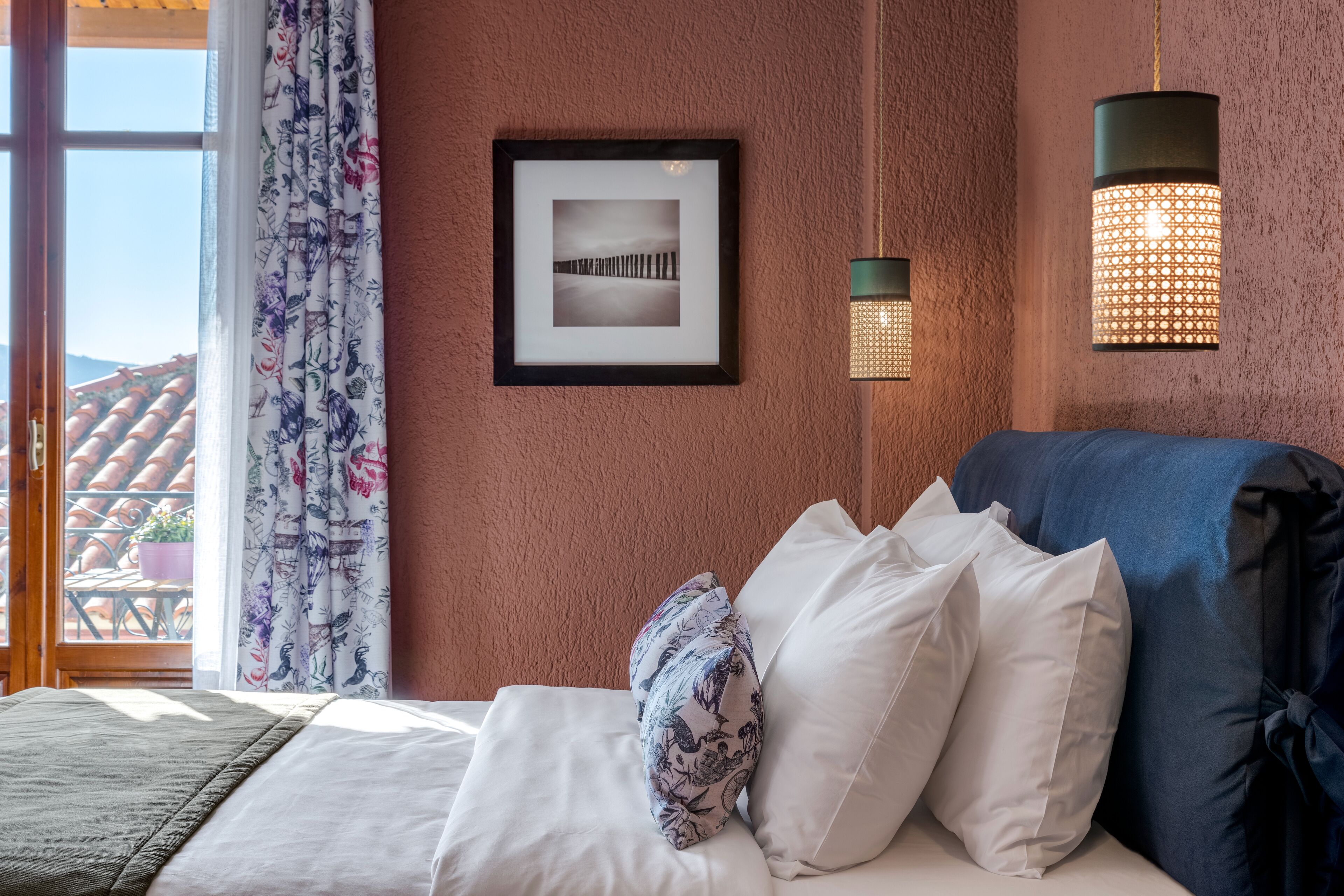 Une chambre à coucher avec un lit, des oreillers, un tableau encadré et un luminaire suspendu.