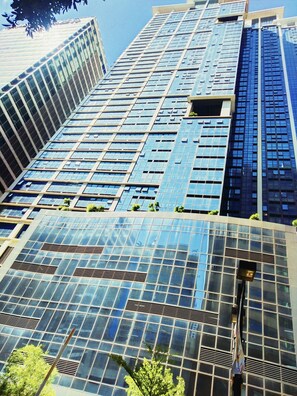 A high-rise building with a modern glass facade, multiple floors, and visible air conditioning vents. - One Eastwood Avenue (Quezon City)
