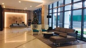 Un hall d’entrée moderne avec un comptoir d’accueil, un sapin de Noël, un espace salon et de grandes fenêtres.
