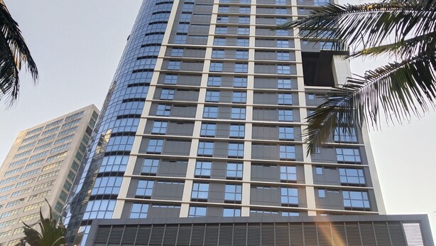 Un gratte-ciel moderne et imposant, doté d’une façade en verre réfléchissant et d’une structure de fenêtres en forme de grille.