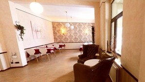 A dining area with tables and chairs, a patterned wallpaper, and a window with a view. - Haus Martens Das Lister Stadthotel (Hannover)
