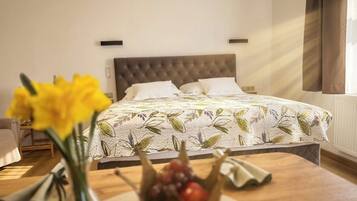 Un dormitorio con una cama, una mesita de noche con un florero y una ventana con cortinas.