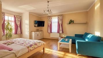 Una habitación con una cama, un sofá, un televisor y una planta.