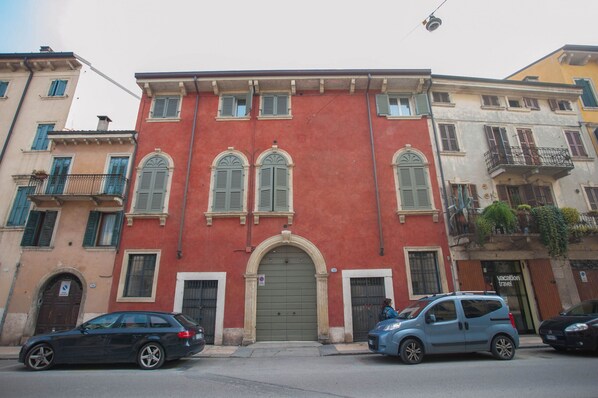 A red building with a green door and multiple windows with shutters. - la vigna in Città il vigneto (Verona)