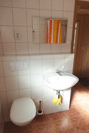 A bathroom with a white toilet, a sink with a mirror above it, and a towel rack with a towel. - Stausee Oberwald (Hohenstein-Ernstthal)