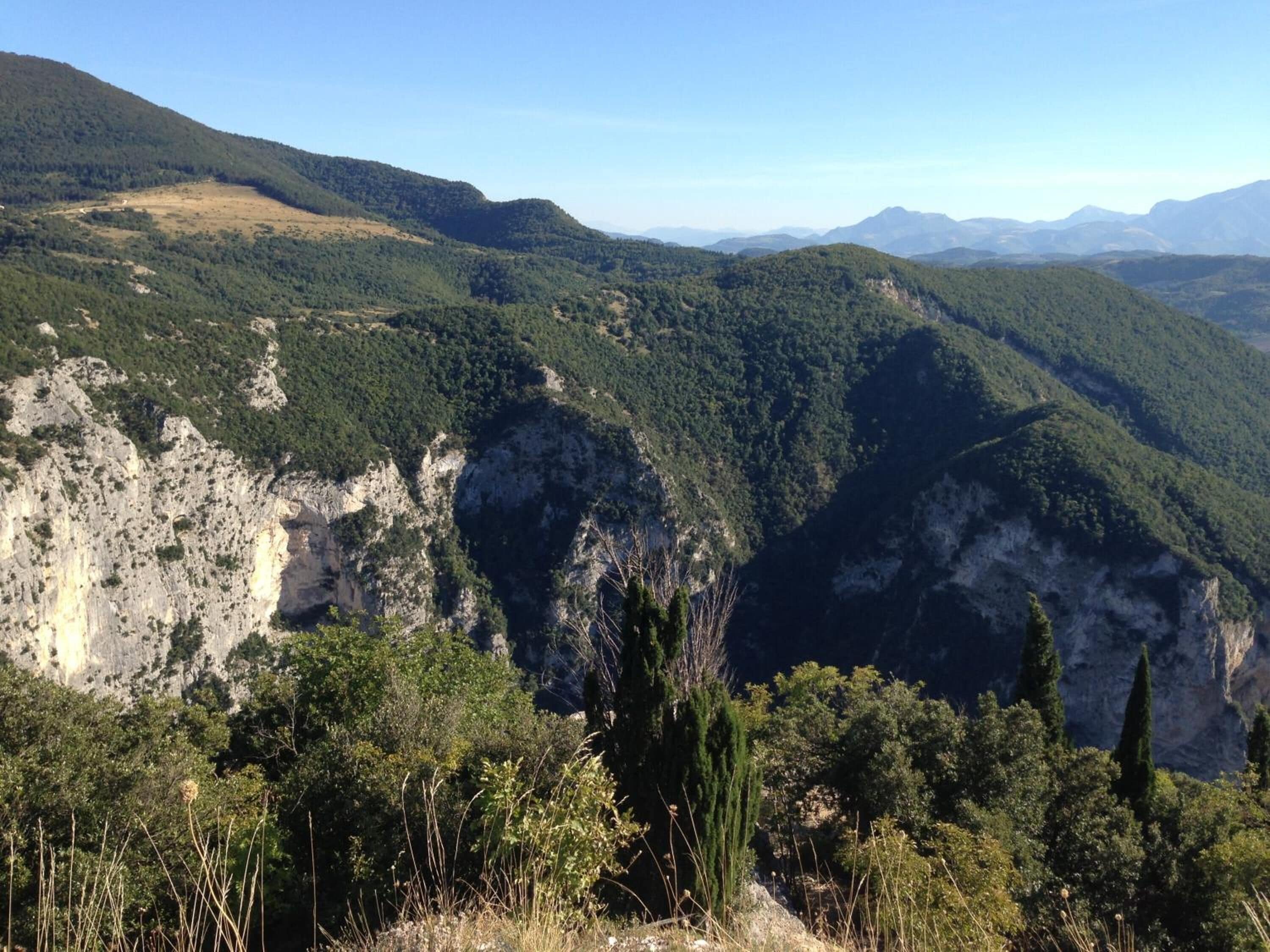 A mountainous landscape with dense forests and rocky cliffs.