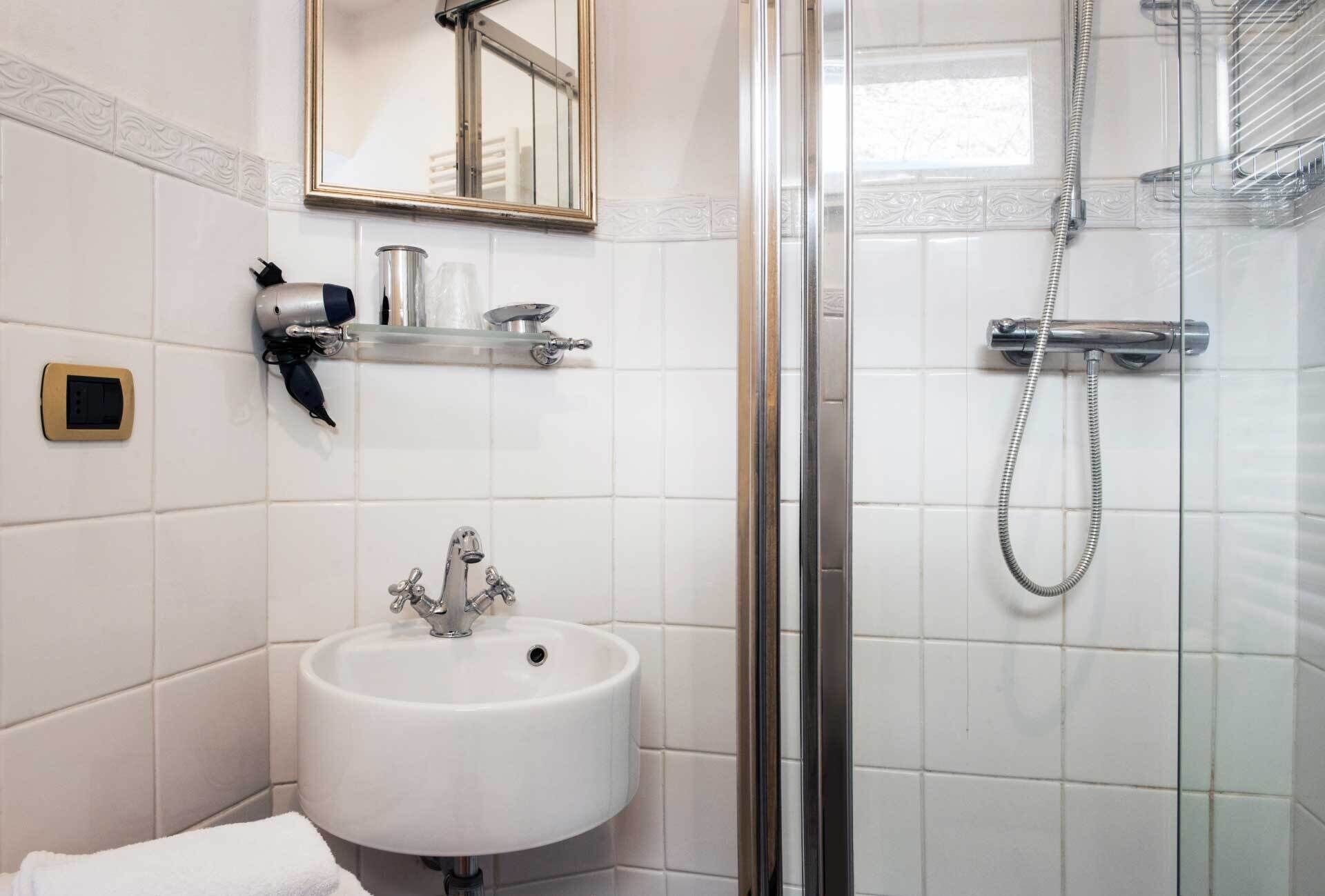 A bathroom with a white sink, a mirror, and a shower.