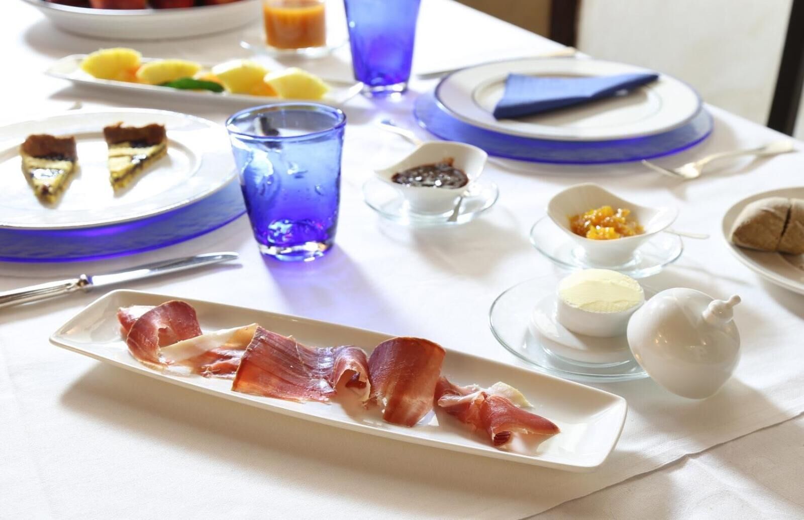 A breakfast setting with plates of food, including bacon, eggs, and fruit.