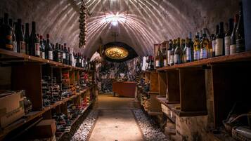 Una bodega subterránea con estantes llenos de botellas de vino y una mesa central.