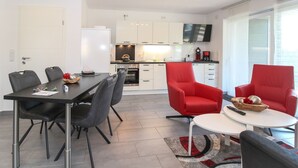 Eine moderne Küche mit weißen Schränken, einem Flachbildfernseher und einem Essbereich mit Tisch und Stühlen.