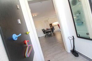 A modern kitchen with a dining area, a blackboard with hooks, and a broom. - Single-storey, high-quality apartment in Greetsiel (Greetsiel)