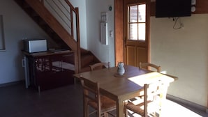 A dining area with a wooden table and chairs, a small decorative vase, a staircase, a television mounted on the wall, and a door with a window. - House with terrace, Avignon festival 12km away, Spirou park and wave island (Le Thor)