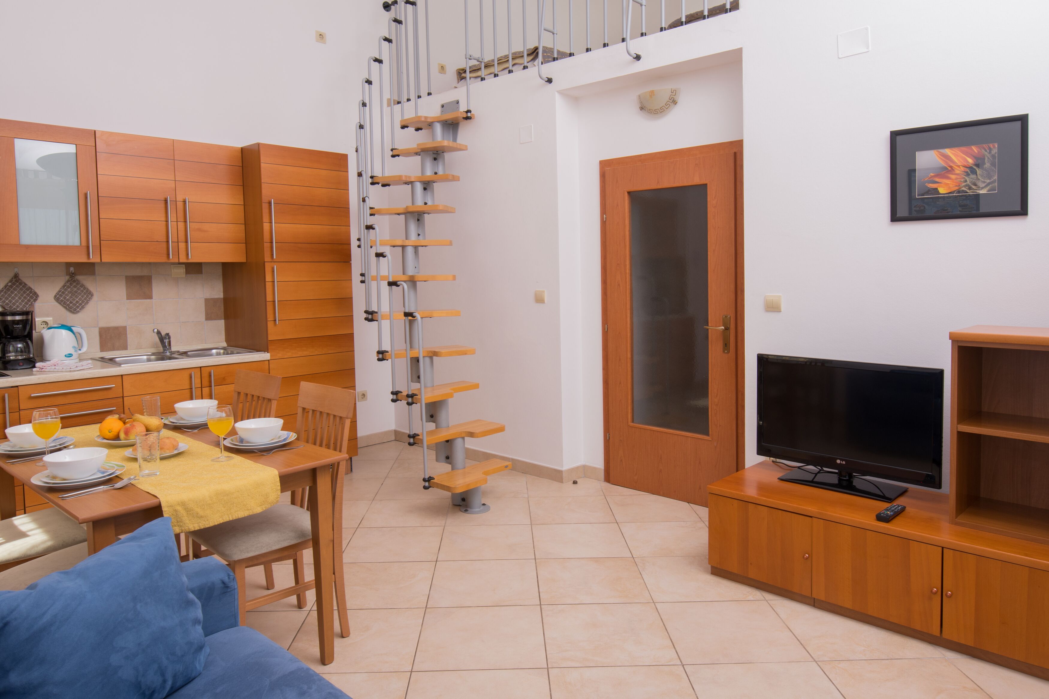 Um espaço compacto para viver, com cozinha, área de refeições e escada para um andar superior.