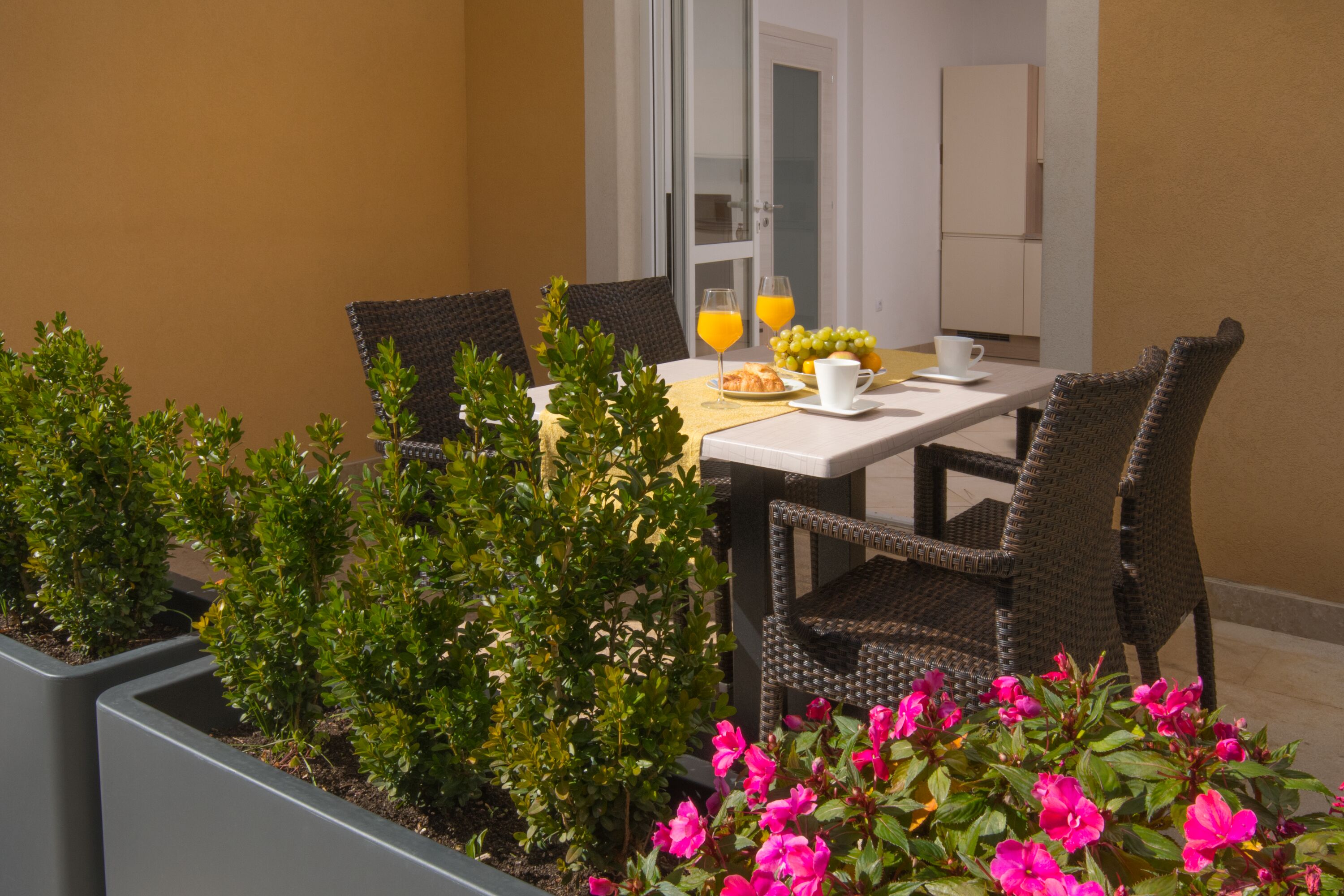 A dining table with chairs, a glass of orange juice, a plate of grapes, and a cup.