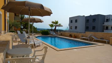 Een seizoensgebonden buitenzwembad, parasols voor strand/zwembad