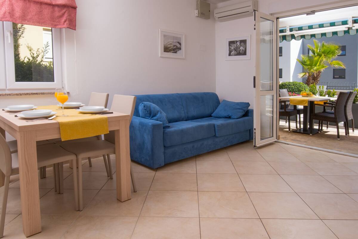 A dining area with a wooden table, blue sofa, and a glass of orange juice.