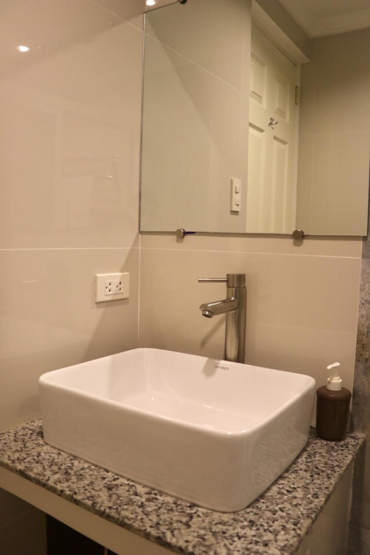 A bathroom with a white sink, a mirror, and a granite countertop.