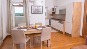 Una cocina moderna con armarios blancos, encimera de madera y comedor con mesa y sillas.