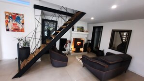Una sala de estar moderna con una escalera, una chimenea y un espejo grande.