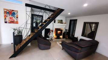A modern living room with a staircase, a fireplace, and a large mirror.