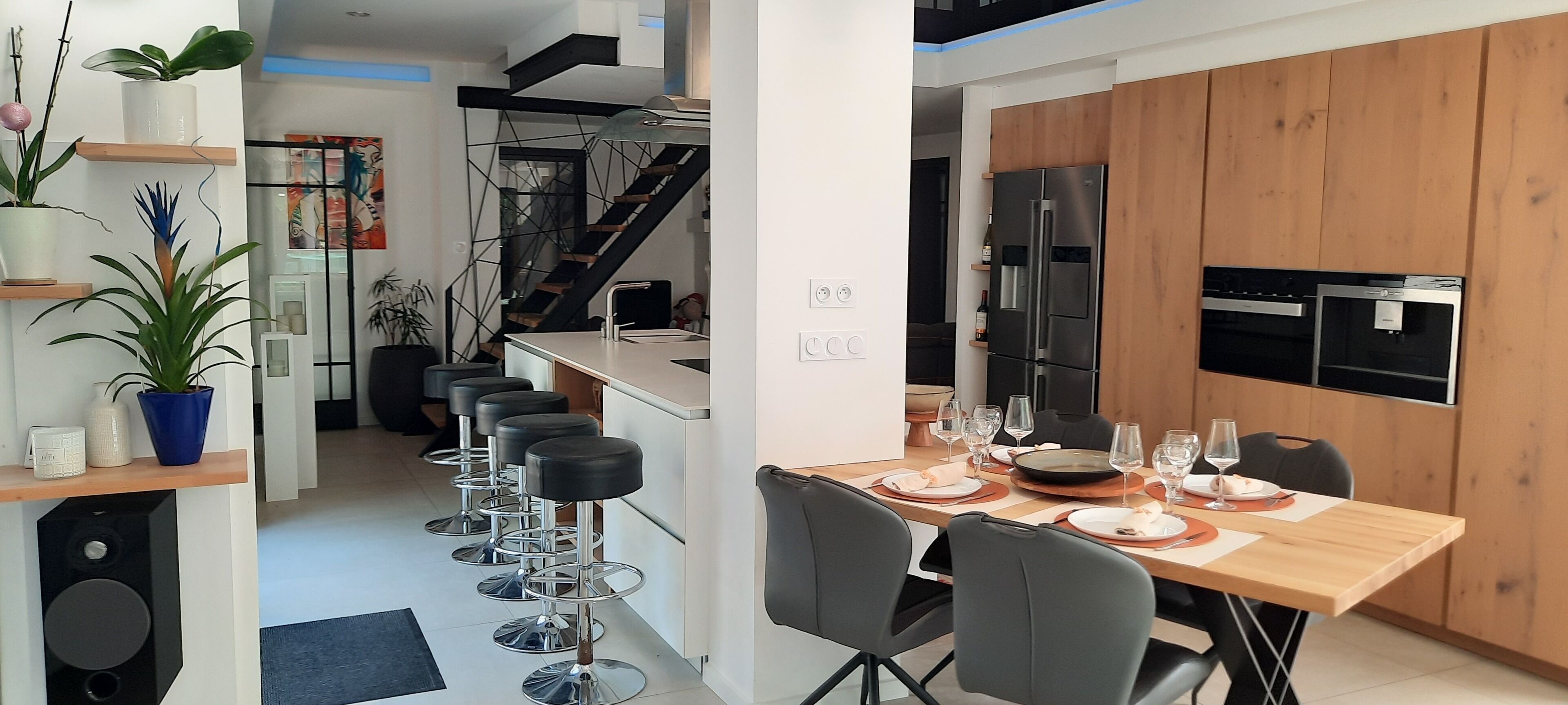 A modern kitchen with a wooden cabinet, stainless steel appliances, and a dining area with a table set for four.