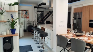 Una cocina moderna con un mueble de madera, electrodomésticos de acero inoxidable y un comedor con mesa para cuatro.