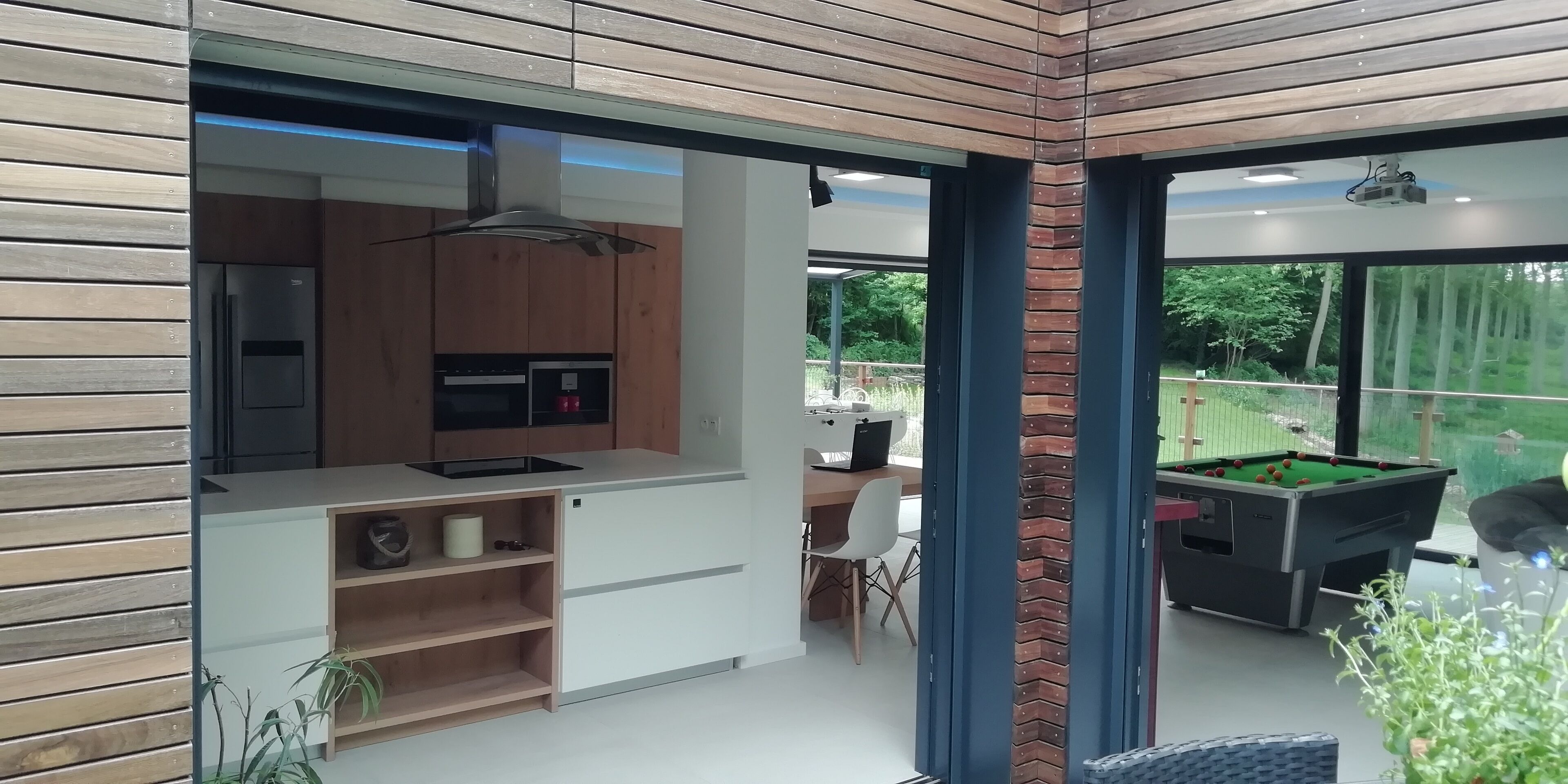 A modern kitchen with a built-in stove, microwave, and a dining area with a table and chairs.
