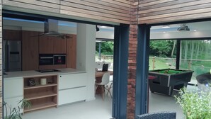 Una cocina moderna con horno empotrado, microondas y comedor con mesa y sillas.