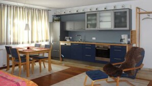 A compact room with a dining table, chairs, a sofa, and a kitchen area including cabinets and appliances. - Apartment 2 in the beautiful Gutenberg / Ostallgäu (Gutenberg)