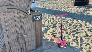 A beachside chair with a number sign, a pink scooter, and another numbered chair in the background.