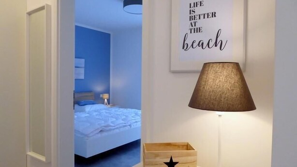 A hotel room with a bed, a bedside lamp, a star-shaped wooden box, and a motivational quote on the wall.