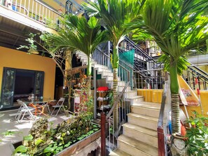 Un espacio interior de varios niveles con una escalera, palmeras y una variedad de plantas.