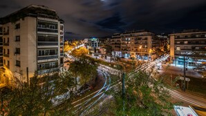 A nighttime cityscape with illuminated buildings and a visible train track. - Acropolis Promenade Apartment (Athens)