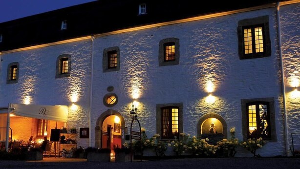 A white building with multiple windows and a covered outdoor seating area. - Hostellerie le Prieuré de Conques (Florenville)