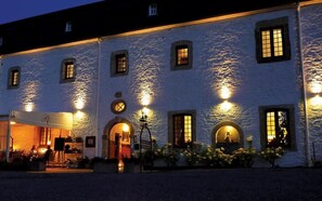A white building with multiple windows and a covered outdoor seating area. - Hostellerie le Prieuré de Conques (Florenville)