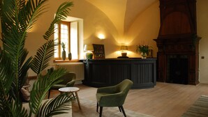 A cozy living room with a fireplace, a comfortable sofa, and a dining table. - Hostellerie le Prieuré de Conques (Florenville)