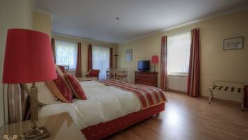 Une chambre d’hôtel avec un grand lit, un bureau, une chaise, une télévision et une fenêtre avec des rideaux.