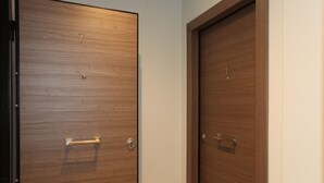 Two wooden doors with handles and numbers, likely indicating room numbers, in a hallway. - Edem Beach Apartment with Mountain view by Athenian Homes (Paleo Faliro)