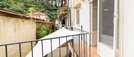 A balcony with a metal railing, a white awning, and a door with a glass panel.