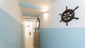Ein Flur mit blauen und weißen Wänden, einem Holzschrank und einem an der Wand befestigten Schiffsschwungrad sowie einem Spiegel.