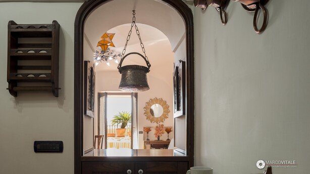 A doorway with a hanging basket, a mirror, and a wall-mounted shelf. - Namily House (Positano)