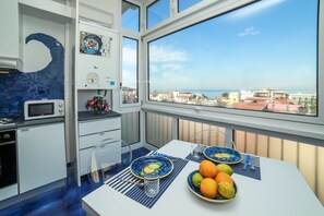 A balcony with a dining table set with plates, bowls, and cutlery, overlooking a coastal cityscape. - Camy House (Sorrento)