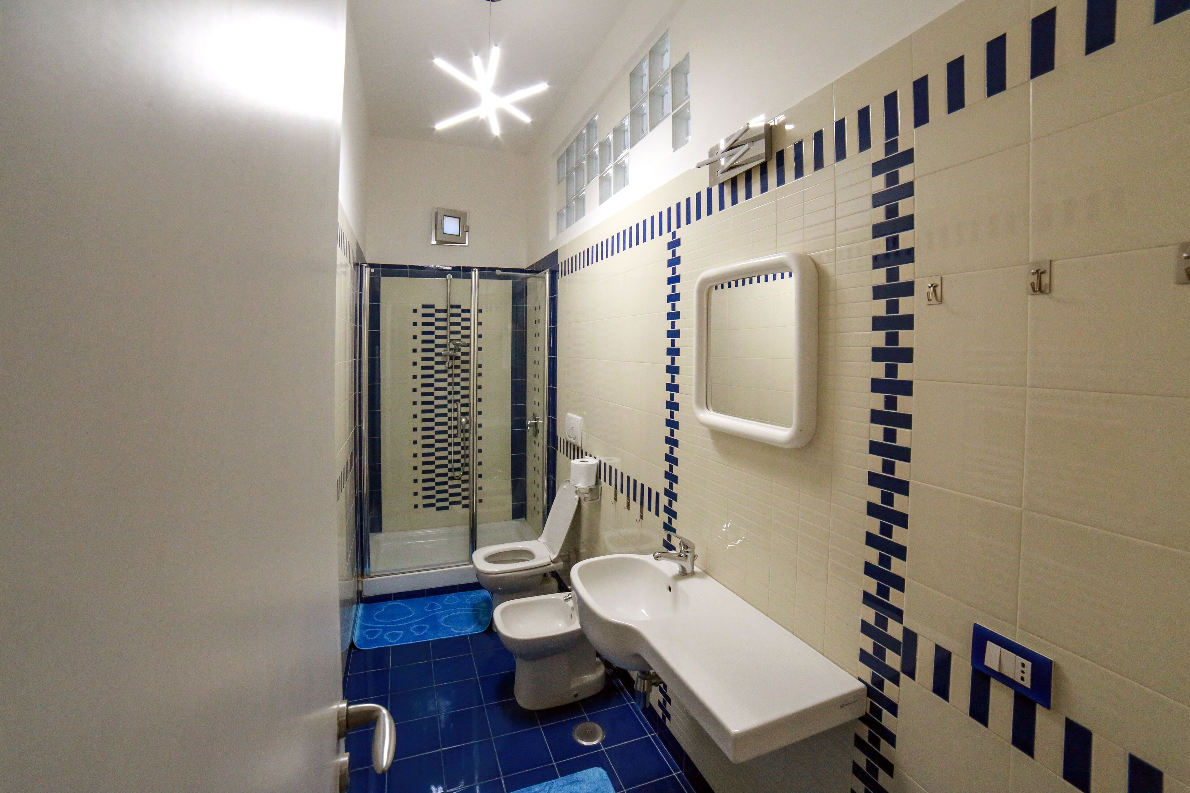 A bathroom with a shower, toilet, and sink, featuring blue and white tiles.